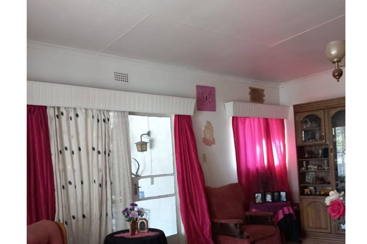 A living room featuring a glass-paneled door with a security gate, built-in curtain pelmets, and a ceiling-mounted light fixture.