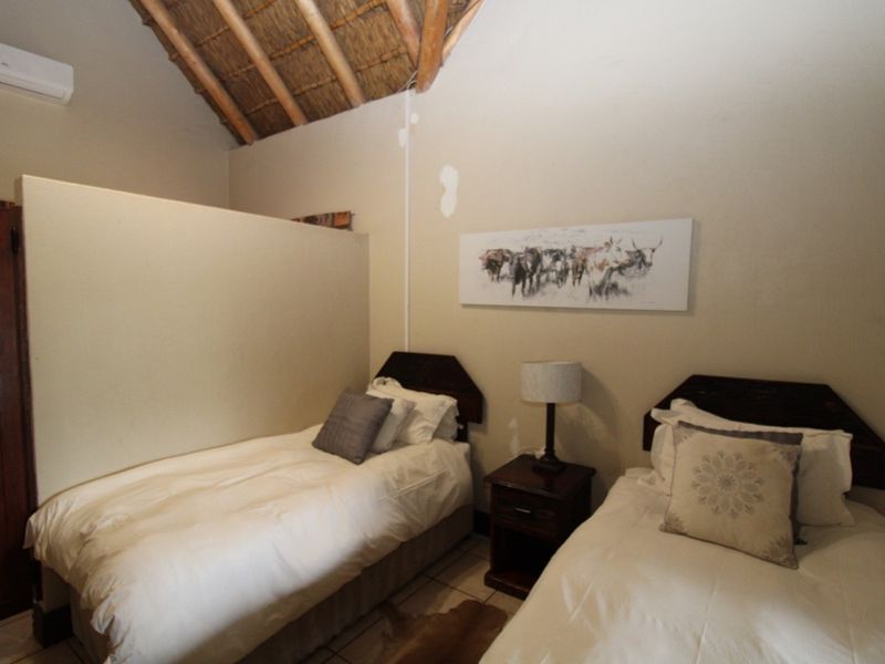 A bedroom featuring an exposed thatch ceiling, tiled flooring, and a wall-mounted air conditioning unit.