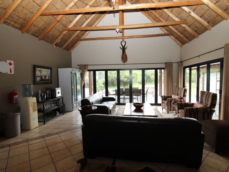 Spacious living area featuring a high vaulted thatched ceiling with exposed timber trusses and large glass sliding doors opening to the outdoors.