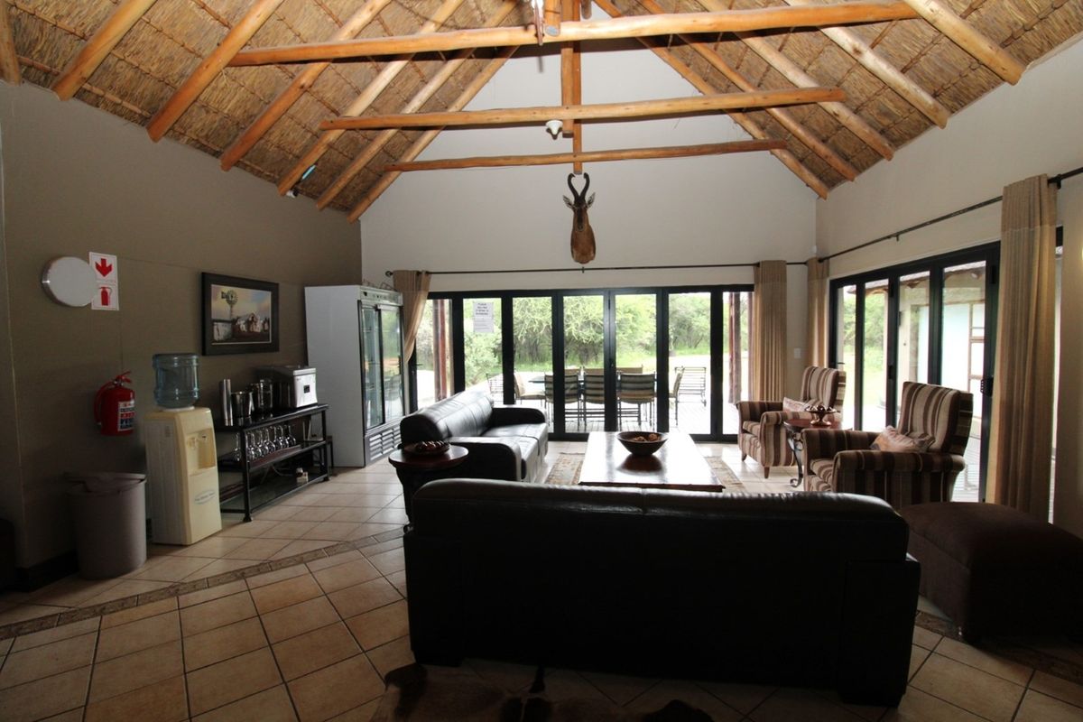 Spacious living area featuring a high vaulted thatched ceiling with exposed timber trusses and large glass sliding doors opening to the outdoors.