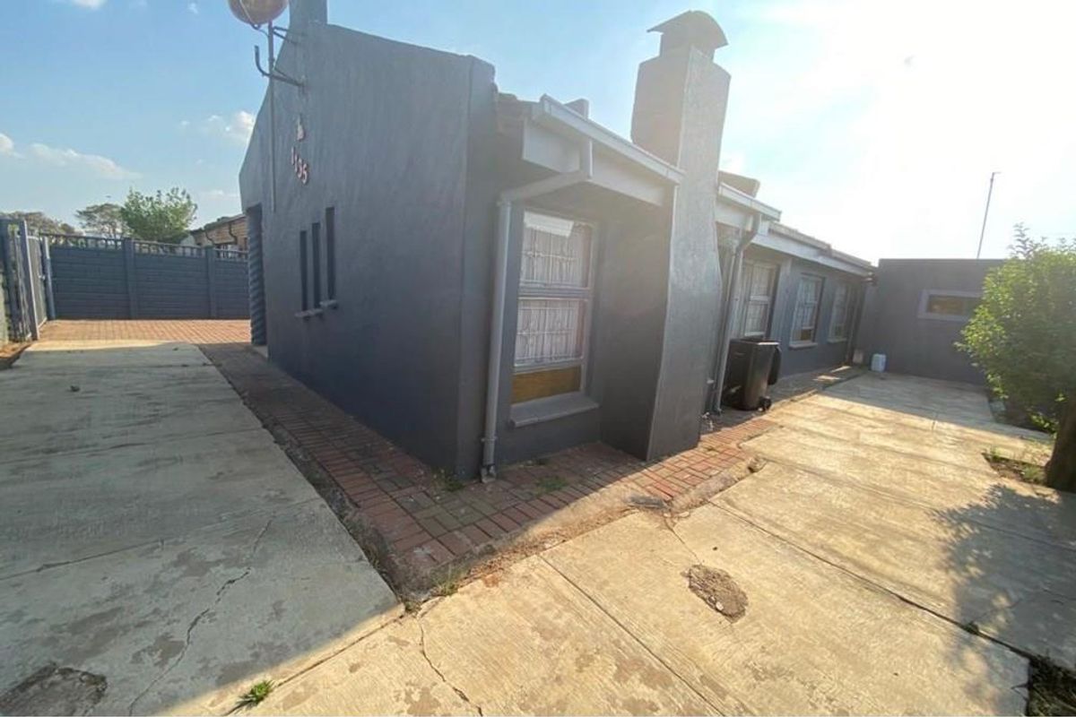 Side view of the property featuring a concrete driveway, paved walkway, and exterior chimney stack.
