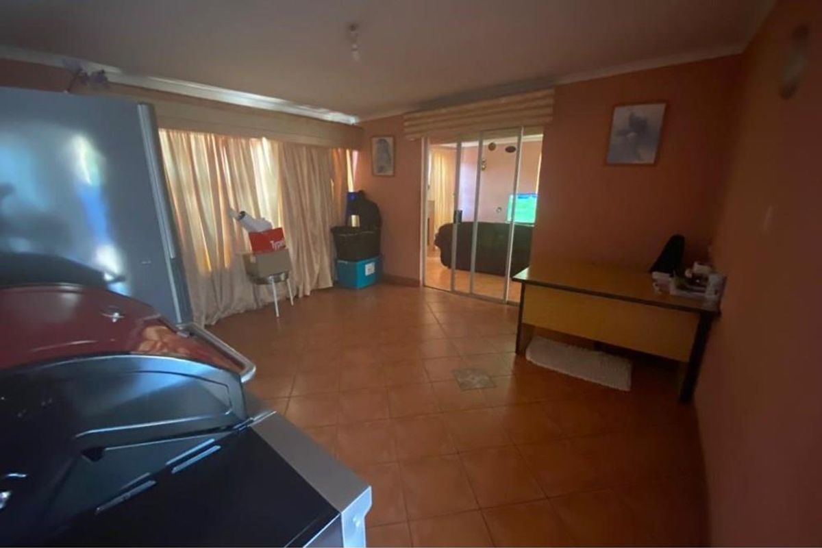 A living area featuring tiled flooring and sliding glass doors leading to an adjacent room.