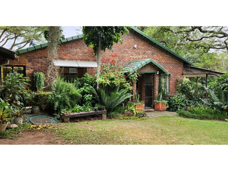A charming face-brick farmhouse exterior featuring a pitched roof, covered entrance, and established garden surroundings.