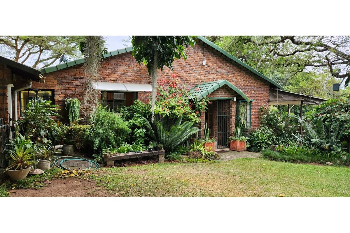 A charming face-brick farmhouse exterior featuring a pitched roof, covered entrance, and established garden surroundings.