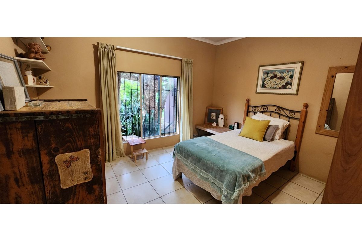 A functional bedroom featuring tiled flooring, a window with security bars, and neutral wall finishes, offering a comfortable and practical living space.