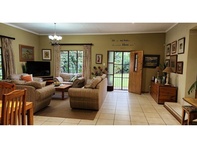 Spacious open-plan living area featuring tiled flooring, large windows, and direct access to the garden through a wooden door.