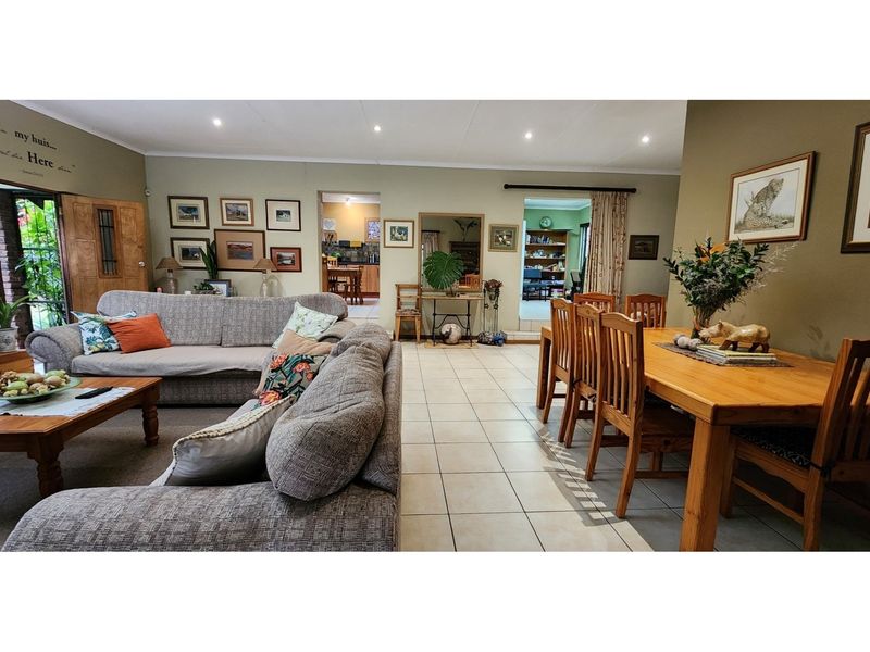 Spacious open-plan living and dining area featuring neutral tiled flooring, recessed ceiling lighting, and direct access to adjacent rooms.