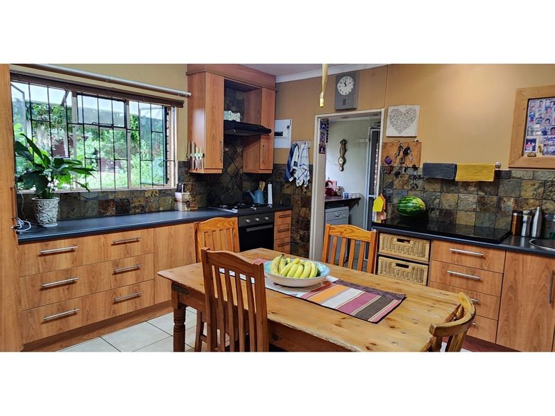 A functional kitchen featuring wood-look cabinetry, dark stone countertops, a tiled backsplash, and an integrated oven with a hob.