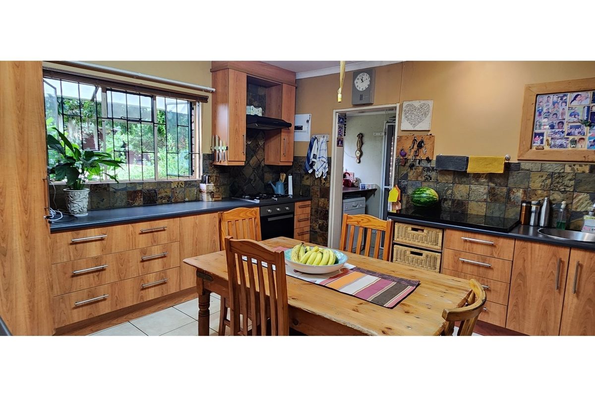 A functional kitchen featuring wood-look cabinetry, dark stone countertops, a tiled backsplash, and an integrated oven with a hob.