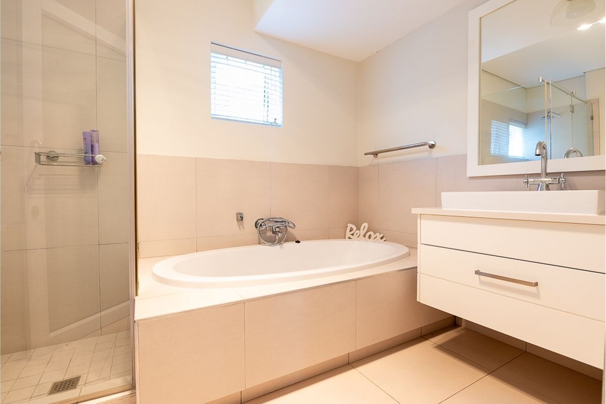 Modern bathroom featuring a built-in bathtub, a separate glass-enclosed shower, and a wall-mounted vanity with a basin and mirror.