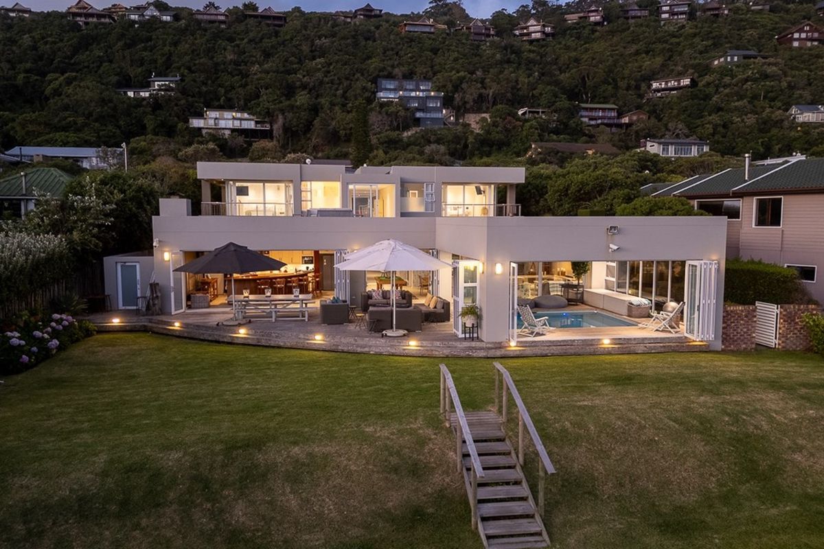 A modern multi-level residence featuring a spacious rear patio, integrated swimming pool, and expansive glass folding doors opening to a landscaped garden.