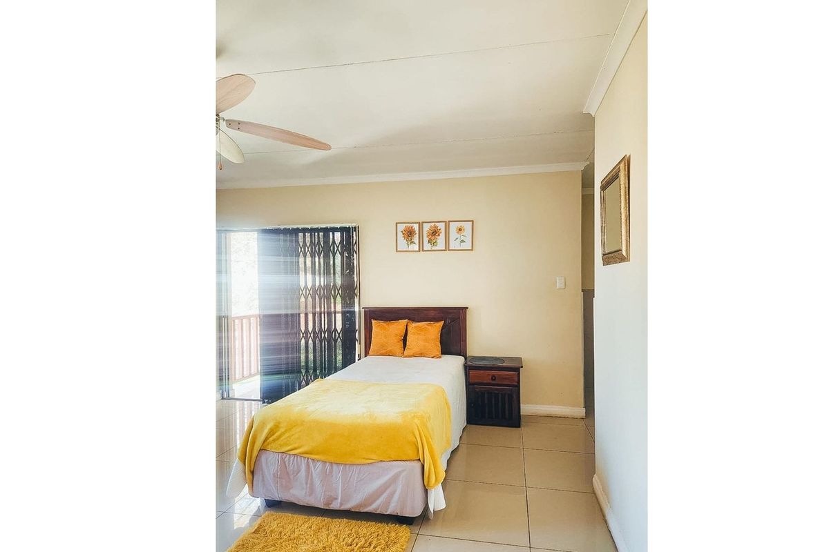 A bedroom featuring tiled flooring, a ceiling fan, and sliding glass doors leading to an outdoor area.