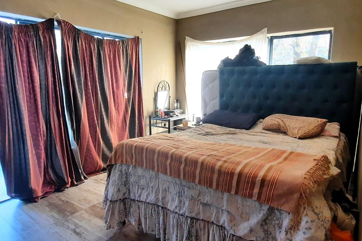 A bedroom featuring tiled flooring and large windows with sliding door access, providing natural light and a connection to the outdoor area.