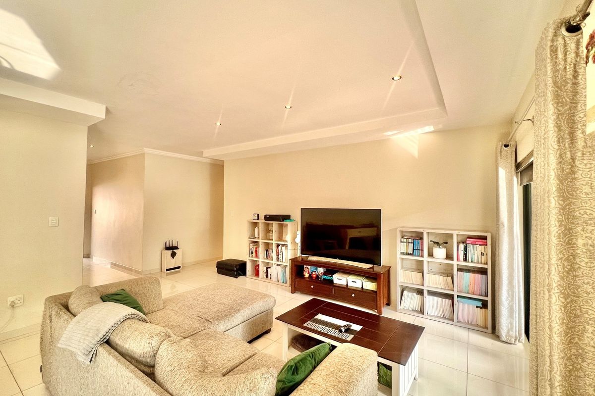 Spacious living room featuring recessed ceiling lighting, tiled flooring, and large windows allowing for ample natural light.