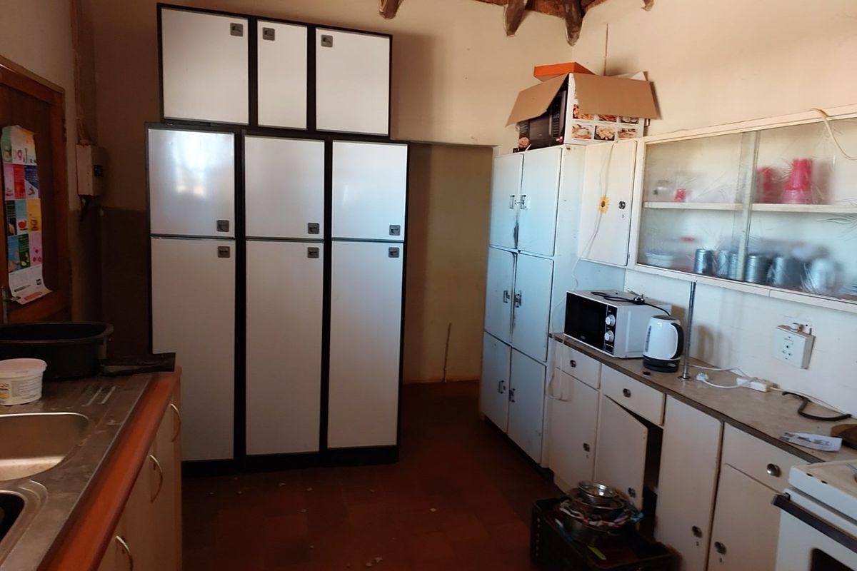 A functional kitchen area featuring extensive built-in cabinetry, a double sink, and tiled flooring, offering a practical layout for food preparation and storage.