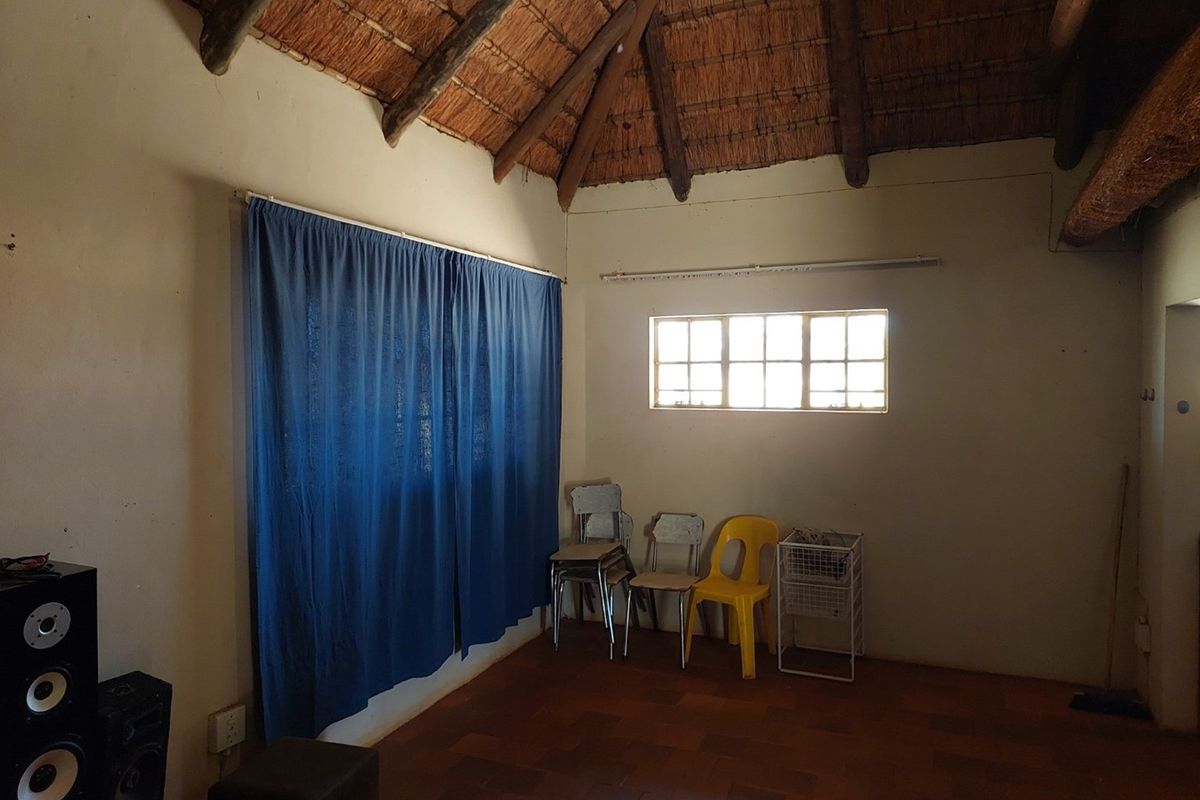A rustic interior space featuring a traditional thatched roof, tiled flooring, and a multi-pane window, offering a simple and authentic aesthetic.
