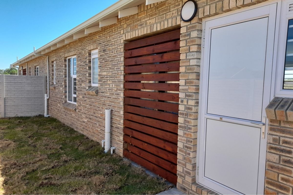 Exterior view of the townhouse side elevation featuring face brick walls, a timber privacy screen, and a white framed door.