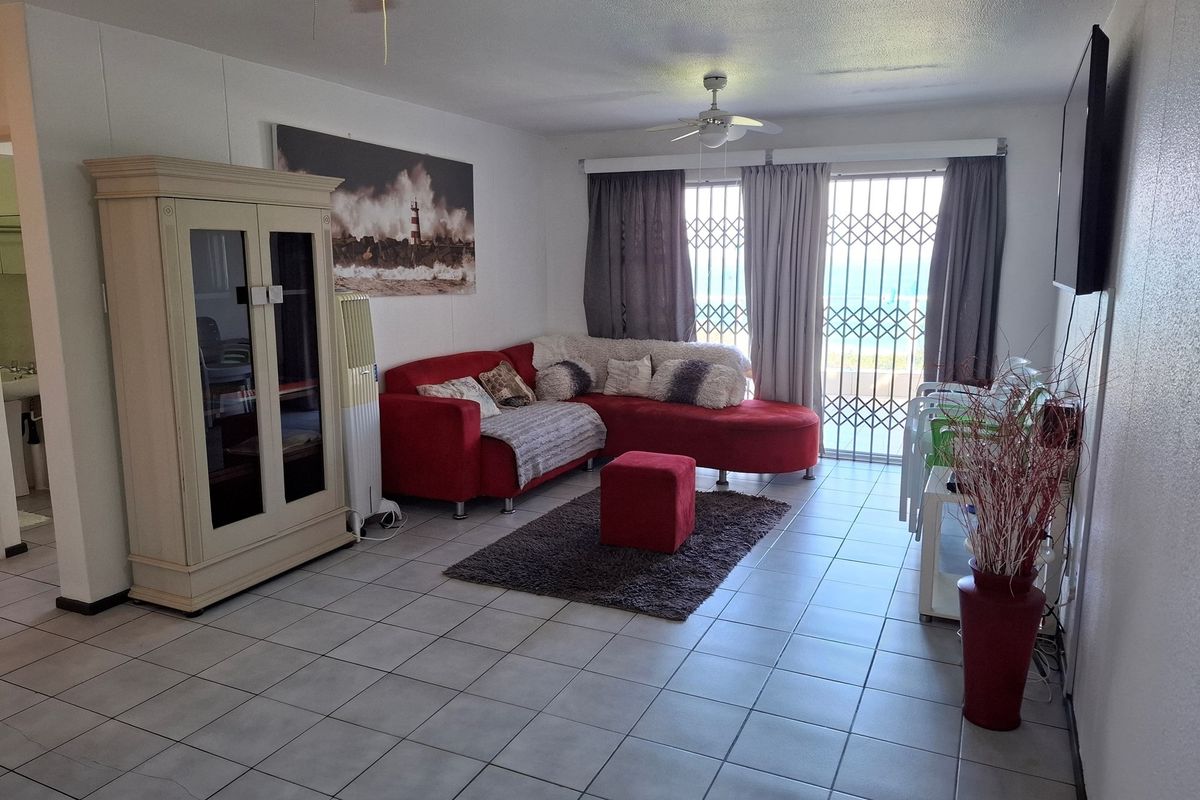 A living room featuring tiled flooring, a ceiling fan, and a sliding glass door with a security gate leading to an outdoor area.