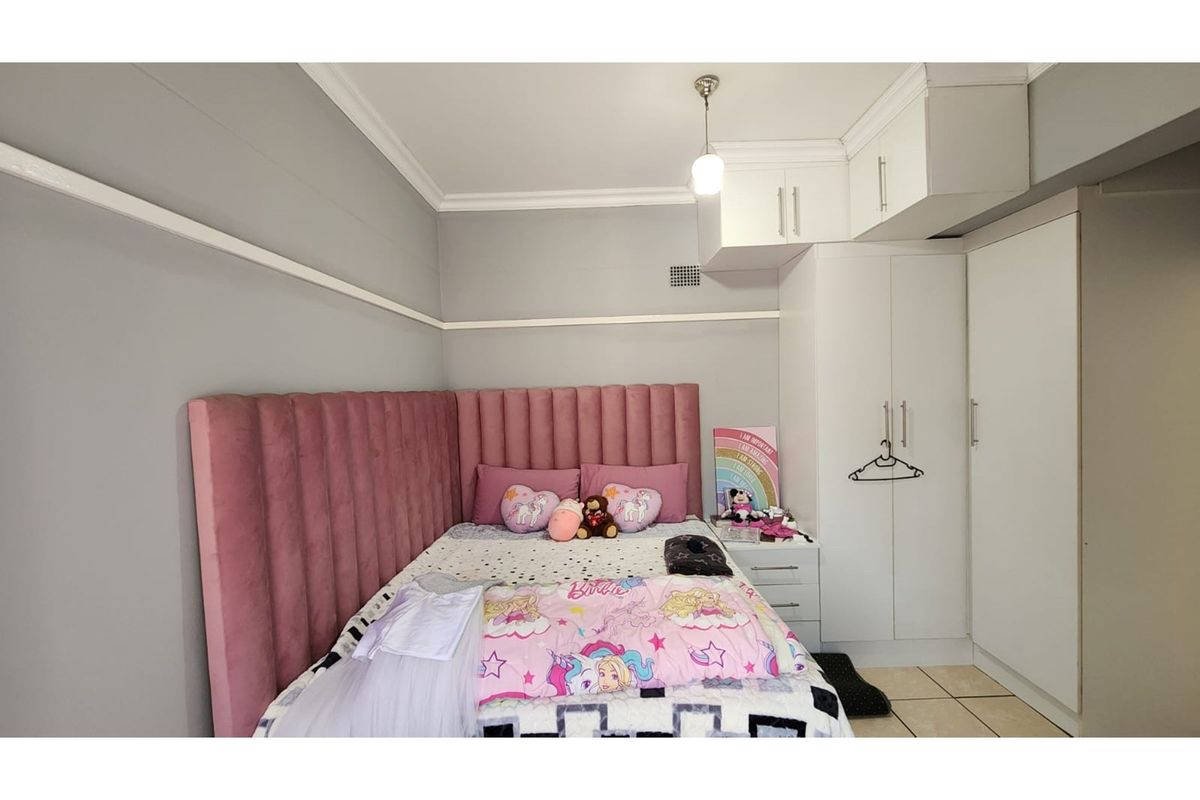 A well-maintained bedroom featuring built-in white cabinetry, overhead storage cupboards, and crown molding, providing efficient storage and a clean aesthetic.