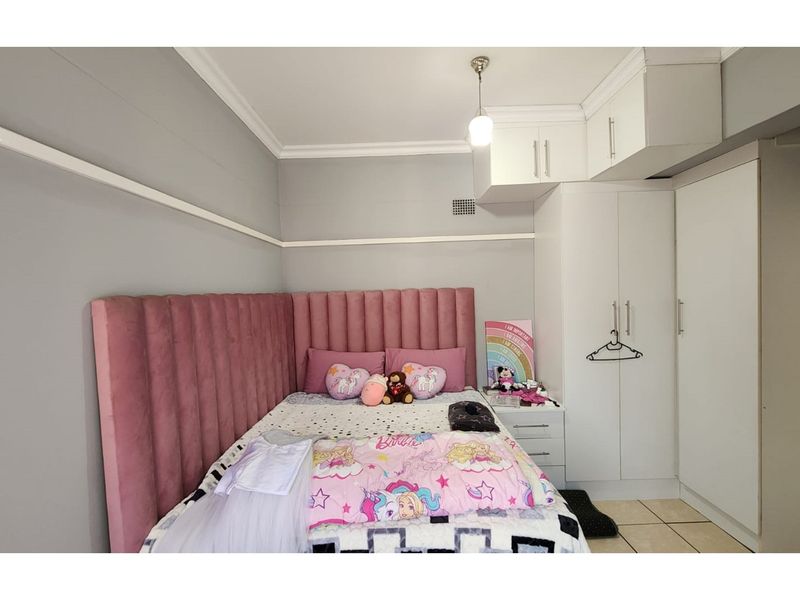 A well-maintained bedroom featuring built-in white cabinetry, overhead storage cupboards, and crown molding, providing efficient storage and a clean aesthetic.