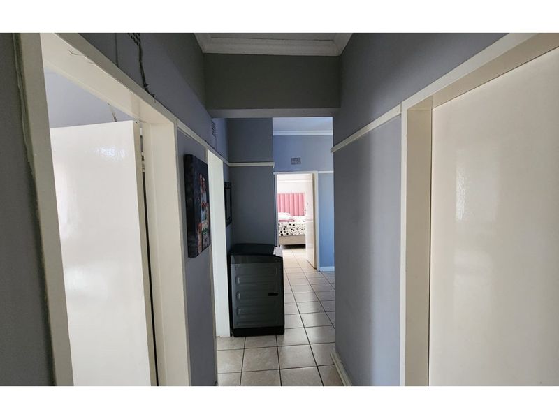 A central hallway with tiled flooring providing access to multiple rooms within the apartment.