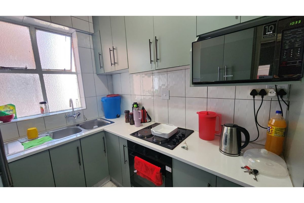 A functional kitchen featuring modern cabinetry, a built-in oven, electric hob, and a double stainless steel sink with tiled splashbacks.
