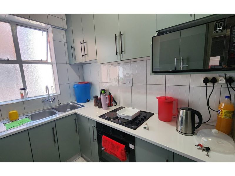 A functional kitchen featuring modern cabinetry, a built-in oven, electric hob, and a double stainless steel sink with tiled splashbacks.