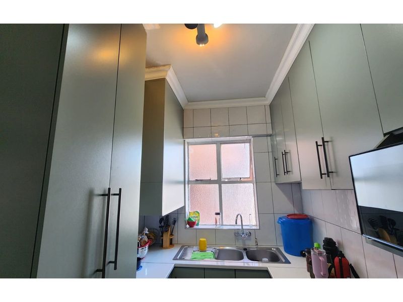 A compact kitchen featuring modern cabinetry, a double-basin stainless steel sink, and tiled splashbacks, providing a functional and efficient workspace.