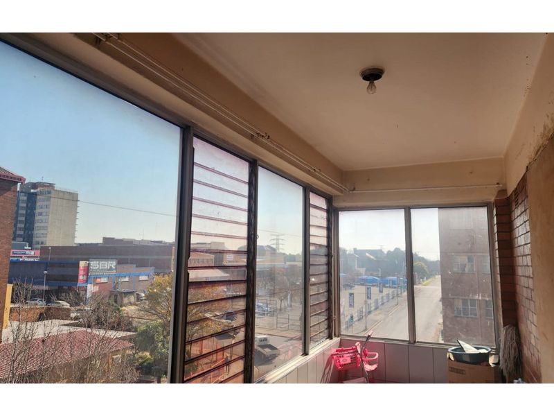Enclosed balcony area featuring large glass windows with urban views, offering potential for a bright sunroom or additional living space.