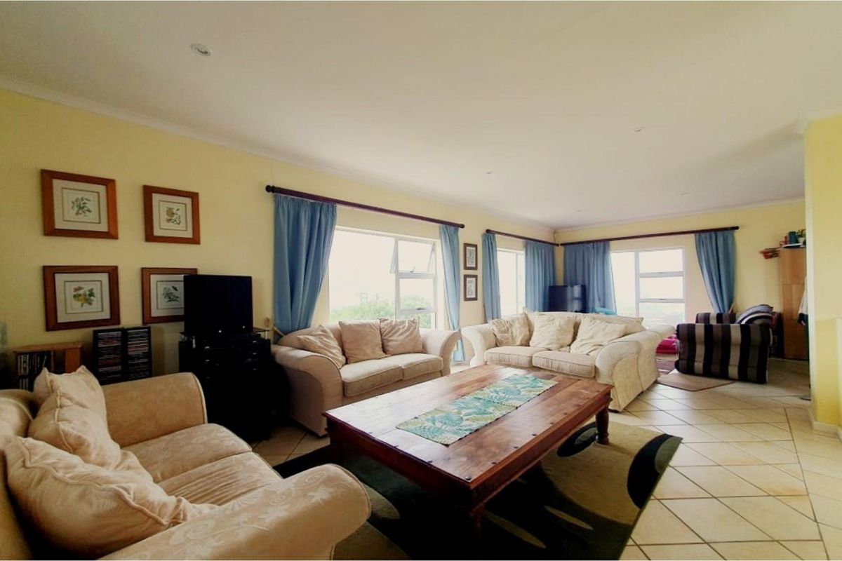 Spacious living room featuring large windows, tiled flooring, and recessed ceiling lighting, offering a bright and comfortable area for relaxation.