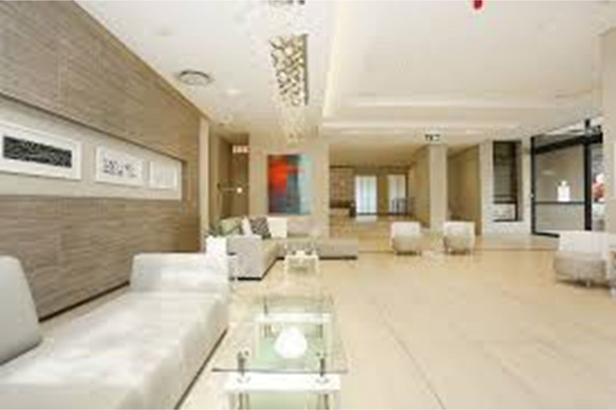 Spacious and modern apartment lobby or communal living area featuring tiled flooring, recessed ceiling lighting, and contemporary wall paneling.