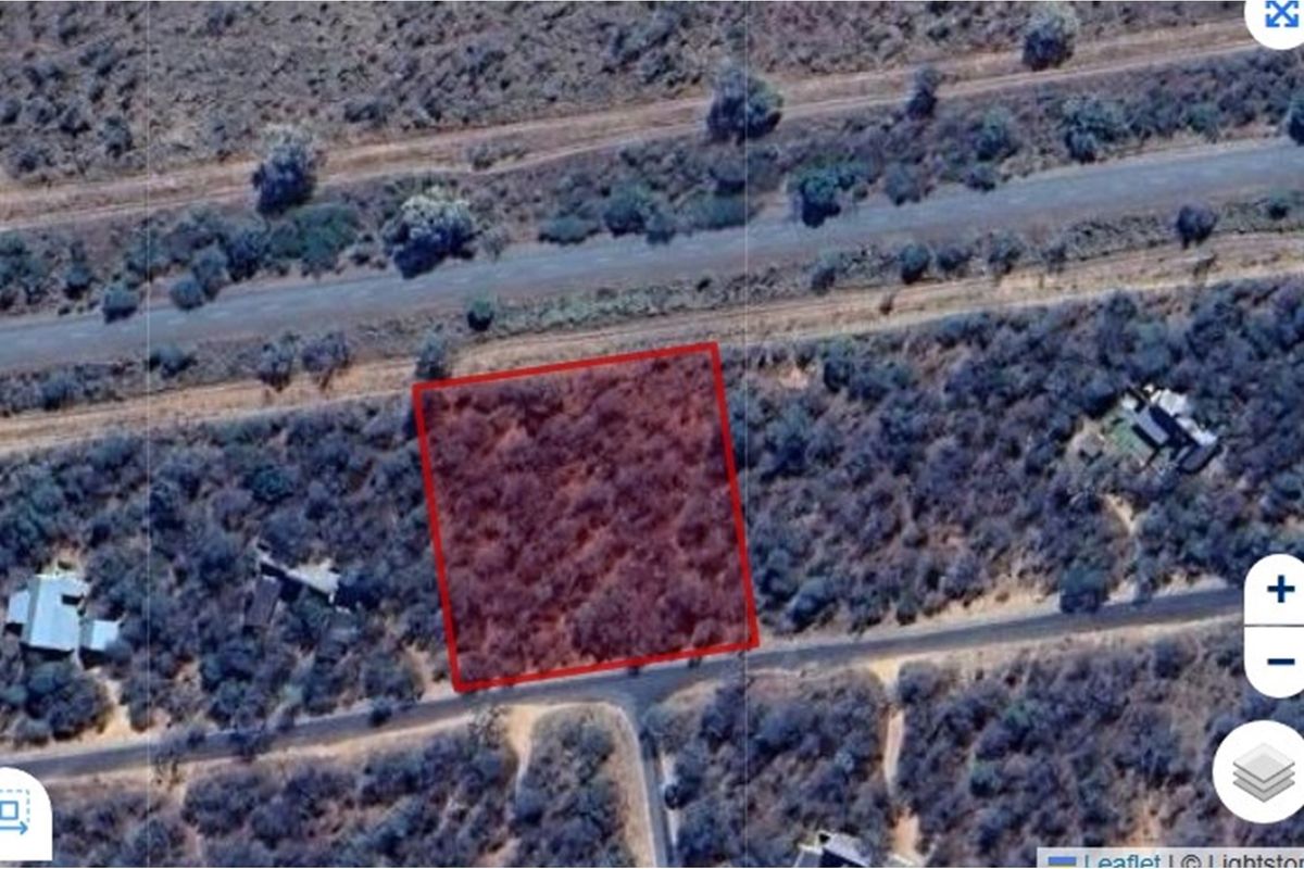 An aerial view of a vacant residential plot highlighted in red, showing natural vegetation and proximity to local road infrastructure.