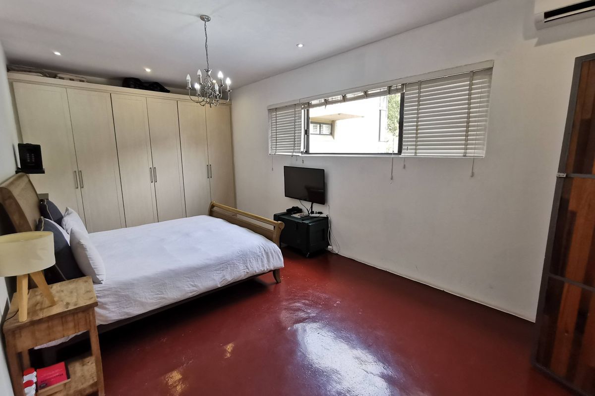 A bedroom featuring built-in cupboards, air conditioning, and venetian blinds, with polished concrete flooring and recessed lighting.
