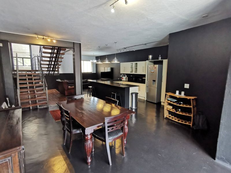 Spacious open-plan living area featuring a modern kitchen with island, polished concrete floors, and a striking staircase leading to the upper level.