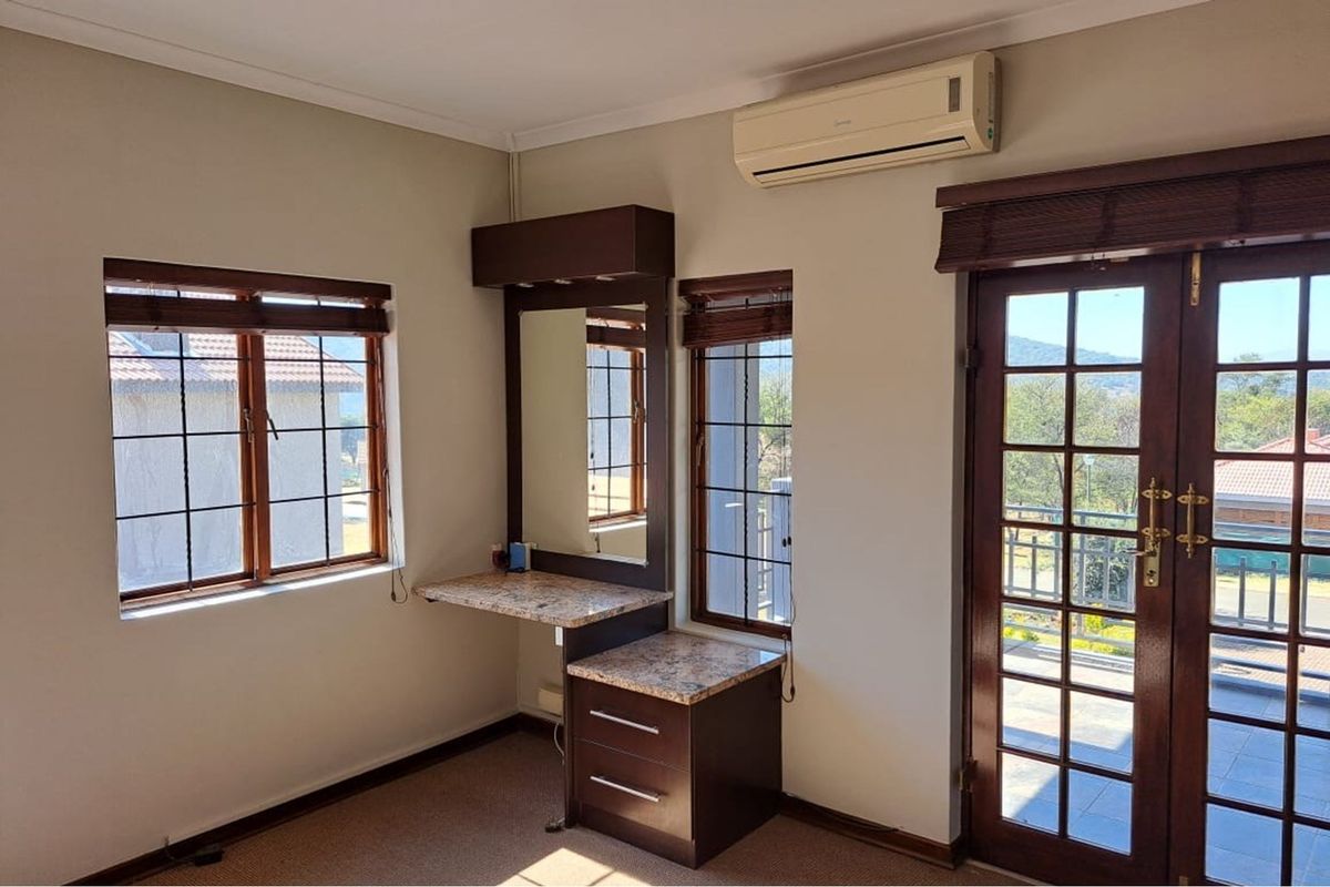 Bedroom featuring a built-in vanity with granite countertop, wooden window frames, and a glass-paneled door leading to an outdoor area.