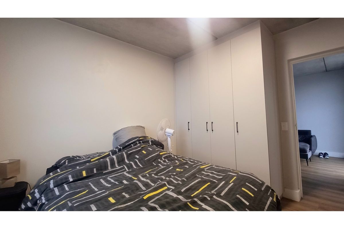 A bedroom featuring neutral walls and floor-to-ceiling built-in cupboards providing ample storage space.