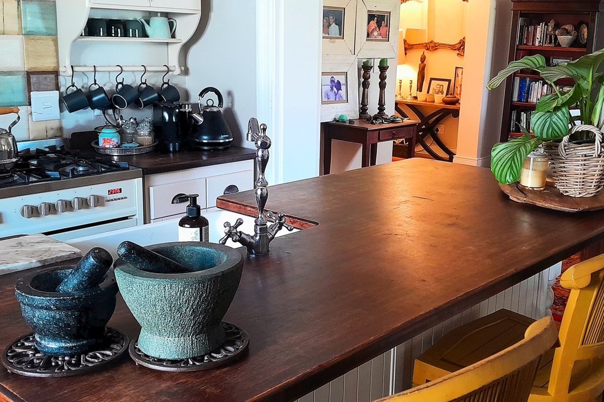 A charming kitchen featuring a large wooden island countertop, a farmhouse-style sink with a vintage-style faucet, and a gas stove with a tiled backsplash.