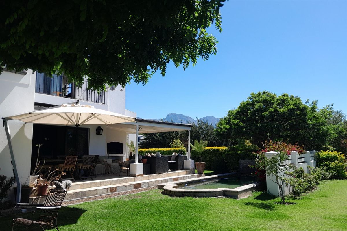 A well-maintained rear garden featuring a covered patio, a small ornamental pond, and scenic mountain views.