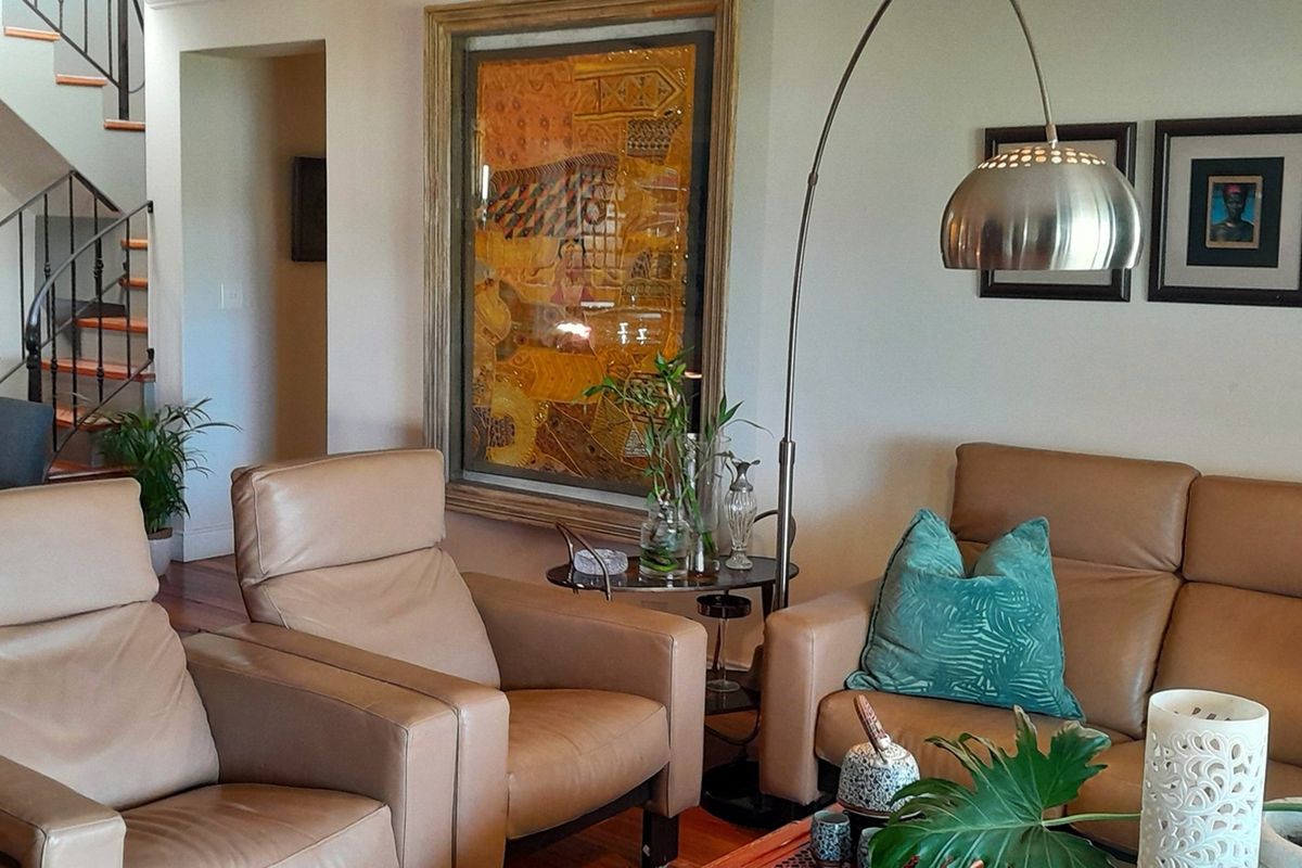 A comfortable living room area featuring hardwood flooring and an open staircase with metal railings leading to the upper level.