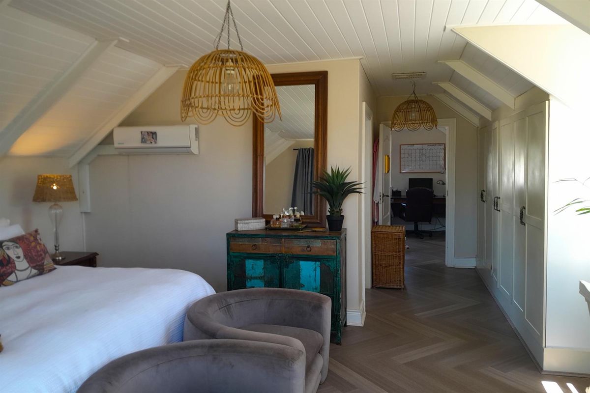 Spacious bedroom featuring vaulted ceilings with timber paneling, built-in cabinetry, herringbone flooring, and a wall-mounted air conditioning unit.