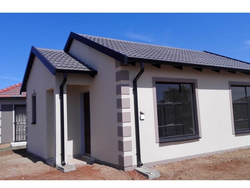 A modern single-story residential house featuring a tiled roof, neutral exterior walls with corner detailing, and dark-framed windows.
