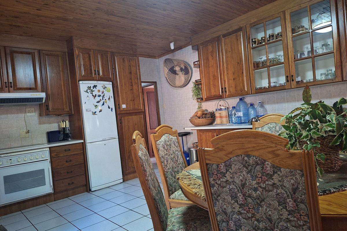 A traditional kitchen featuring extensive timber cabinetry, tiled flooring, and a wood-paneled ceiling, offering a warm and classic aesthetic.