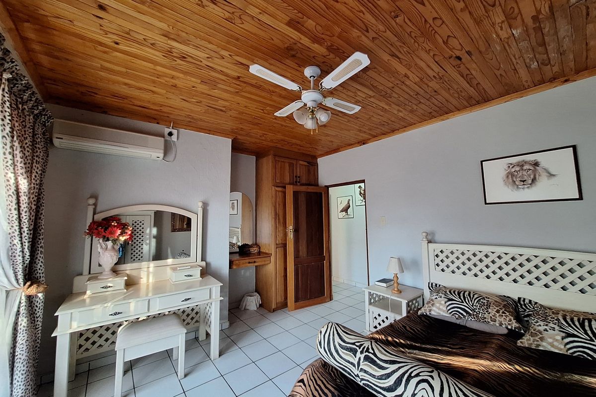 A bedroom featuring a wooden plank ceiling, tiled flooring, built-in wooden cabinetry, and a wall-mounted air conditioning unit.