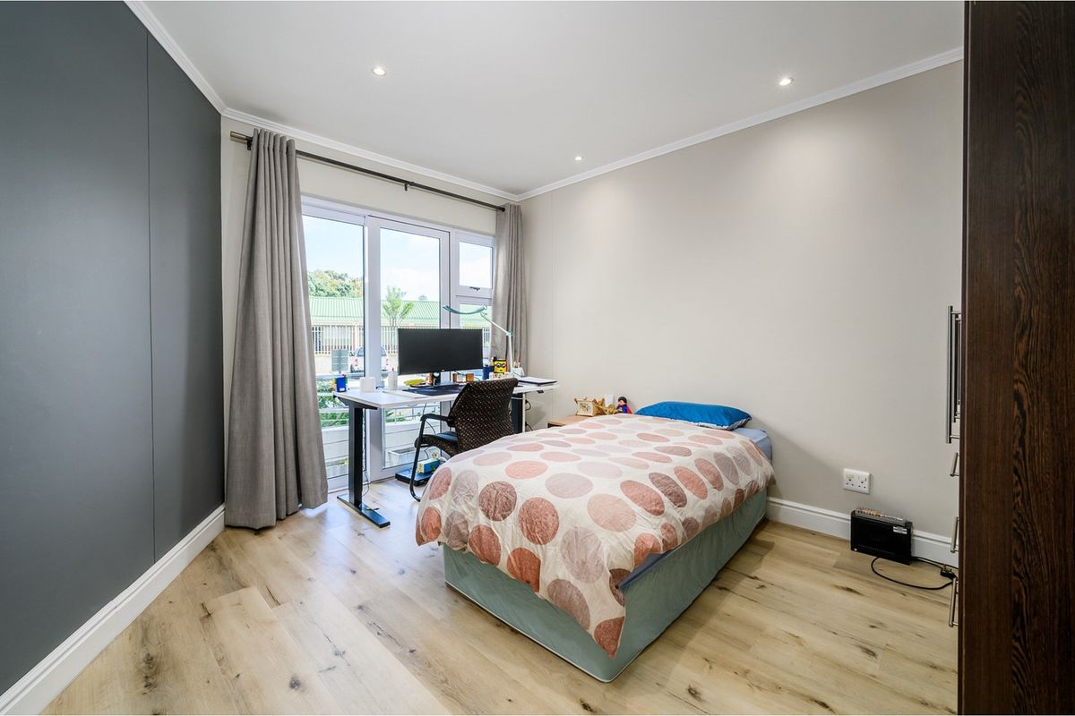 A well-maintained bedroom featuring light wood-look flooring, recessed ceiling lighting, and a glass door providing access to an outdoor area.