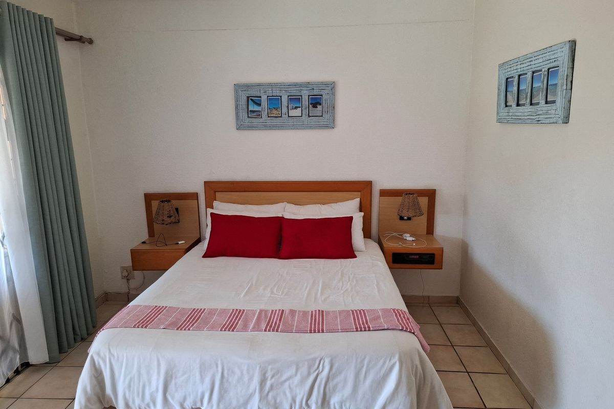 A bedroom featuring built-in wooden bedside tables and tiled flooring, providing a functional and neutral space.