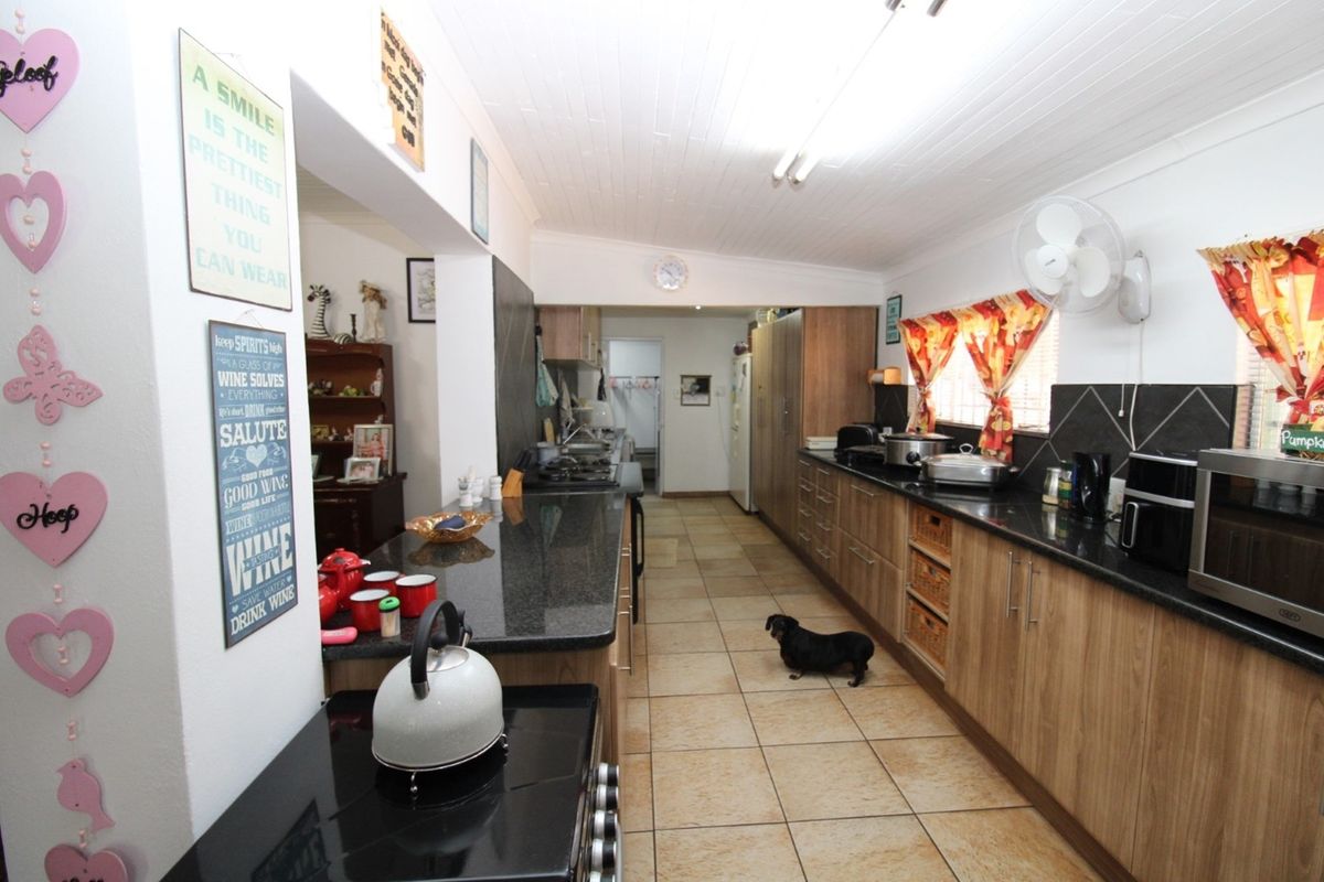 A functional kitchen featuring dark granite countertops, wood-finish cabinetry, tiled flooring, and a breakfast bar area.