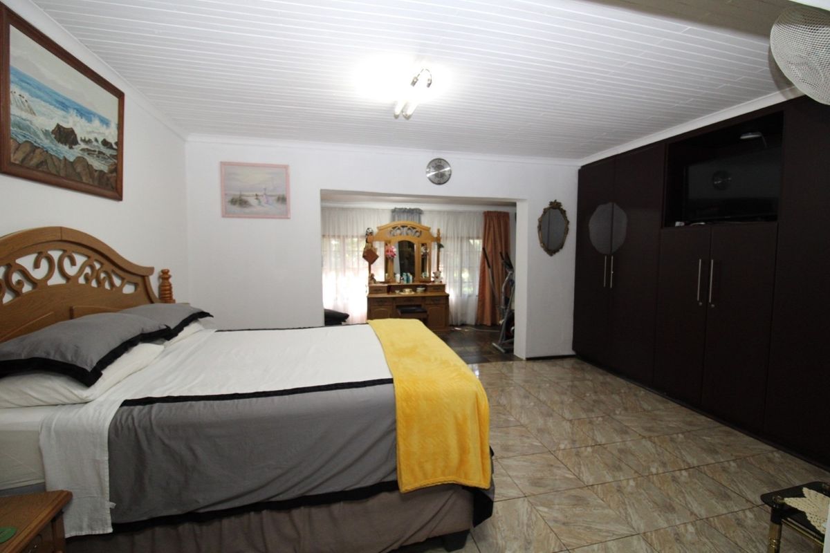 Spacious bedroom featuring tiled flooring, built-in dark wood cabinetry, and a large window area with natural light.