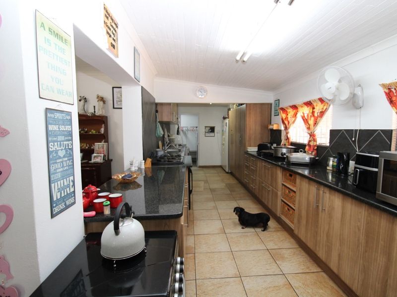 A functional kitchen featuring dark granite countertops, wood-finish cabinetry, tiled flooring, and a breakfast bar area.