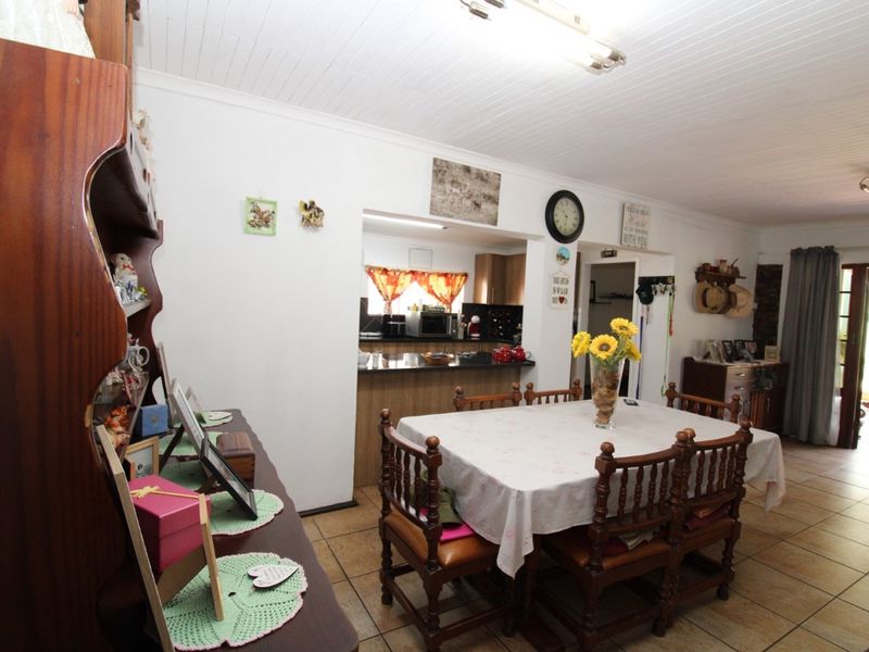 Open plan dining area featuring tiled flooring and a pass-through window connecting to the kitchen space.