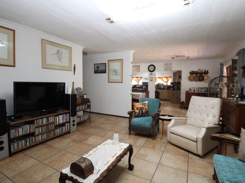 An open-plan living area featuring tiled flooring and a tongue-and-groove ceiling, seamlessly connecting to the kitchen space in the background.
